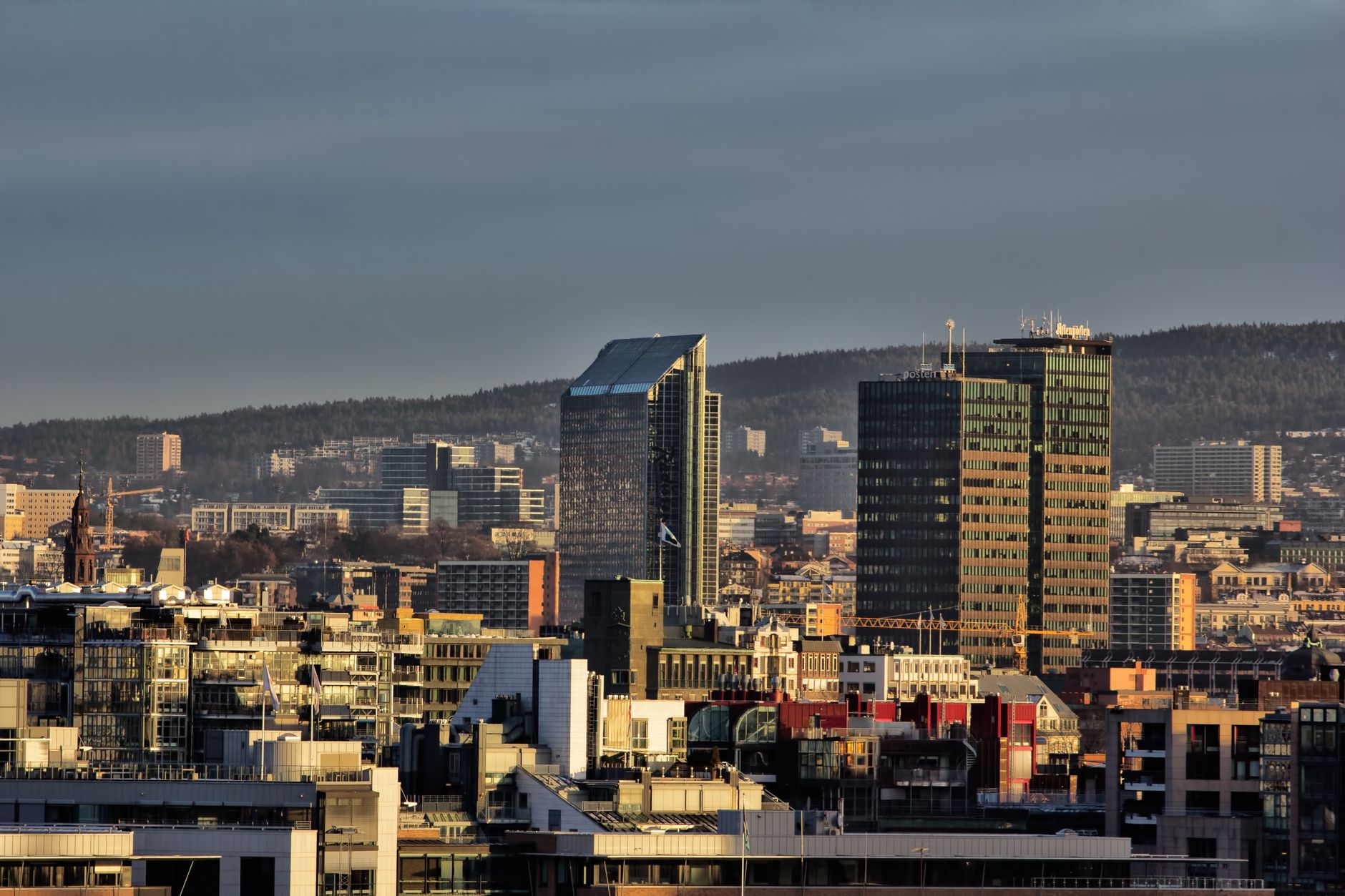 Panorama Oslo o zmierzchu z nowoczesnymi wieżowcami pod dramatycznym niebem