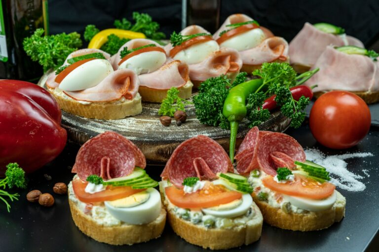 Otwarte kanapki z salami, szynką, jajkiem i pomidorem na rustykalnym stole